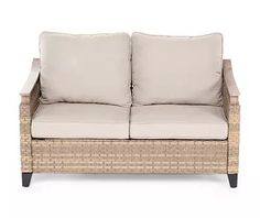 a wicker couch with two pillows on it