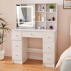 a white desk with drawers and a mirror on it next to a potted plant