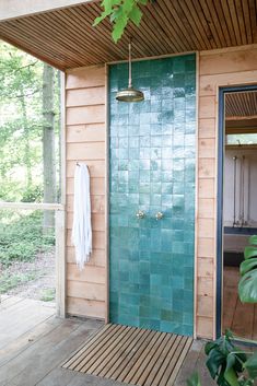 a green door with a towel hanging on it's side in front of a wooden building