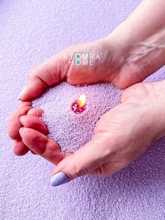 a person holding a small candle in their hands on a purple towel with the word mom written across it