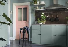 a kitchen with blue walls and pink doors, two stools in front of the counter