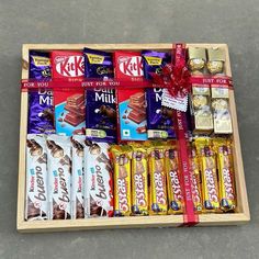 a wooden box filled with assorted chocolates and candy bar wrappers next to a red ribbon