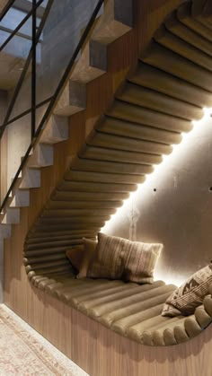 a curved staircase in the middle of a living room next to a couch with pillows on it