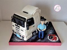 a cake with a man standing next to a truck