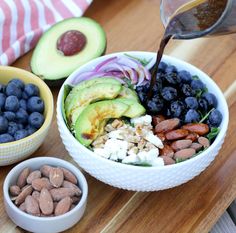 blueberries, avocado, almonds and other foods are being poured into a bowl