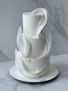 a three tiered white wedding cake sitting on top of a marble slabd counter