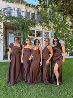 the bridesmaids are wearing brown dresses and posing in front of a large building