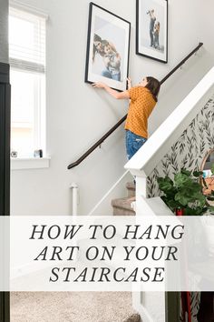 a woman climbing the stairs in her home with text overlay reading how to hang art on your staircase