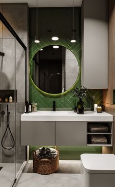 a modern bathroom with green tile on the wall and white countertop, along with a round mirror above the sink