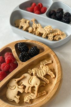 two wooden trays filled with cookies and raspberries on top of a table