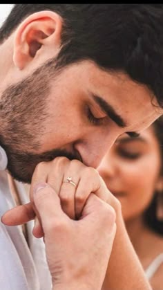 a man and woman standing close to each other with their hands clasped in front of their faces