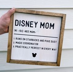 a hand holding up a sign that says disney mom on it's front door