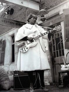 a woman standing in front of a building with a guitar