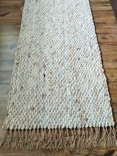 a white rug with fringes on top of a wooden floor