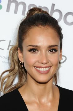 a close up of a person with a smile on her face and hair in a ponytail