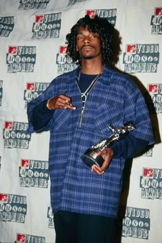 a young man holding an award in his right hand and wearing a plaid shirt on the other