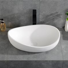 a white sink sitting on top of a counter next to a vase with flowers in it