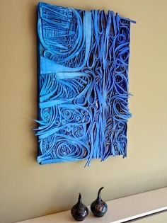 two vases are sitting on a shelf in front of a blue wall art piece