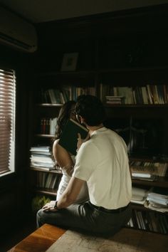 a man and woman sitting in front of a bookcase with books on the shelves