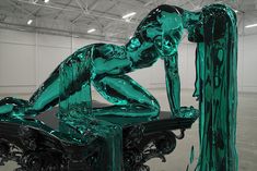 a green sculpture sitting on top of a black table in a warehouse building with white walls