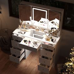 a white vanity table with drawers and lights on it in front of a christmas tree