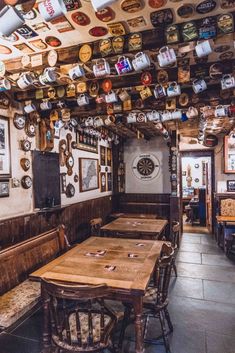 the interior of a restaurant with many plates hanging from the ceiling and wooden tables in front of them