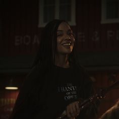 a woman with long hair smiling and holding a guitar