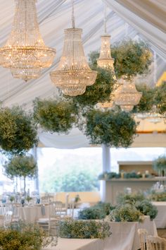 several chandeliers hanging from the ceiling in a room with white tables and chairs