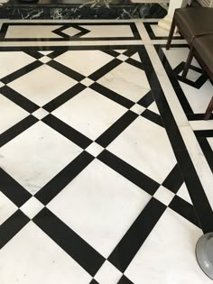 a black and white checkered floor with two chairs in the corner next to it