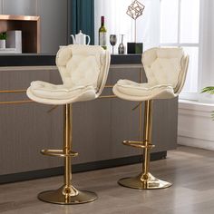 two white and gold bar stools in front of a counter