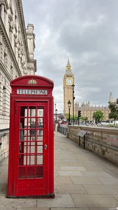 a red phone booth sitting on the side of a road