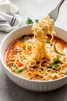 a spoonful of noodles being lifted from a bowl