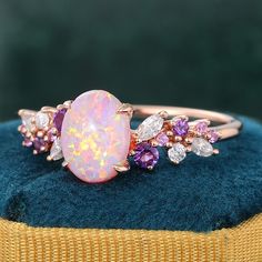 an opal and diamond ring sits on top of a blue velvet box with a gold band