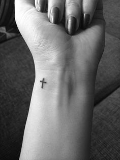 a woman's arm with a small cross tattoo on the left side of her wrist