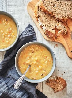 two bowls filled with soup next to slices of bread