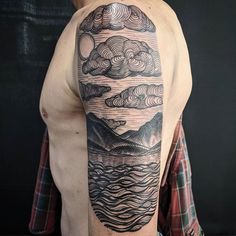 a man with a tattoo on his arm that has clouds and mountains in the sky