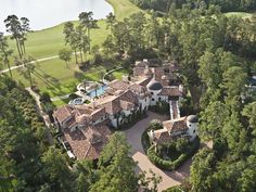 an aerial view of a mansion surrounded by trees