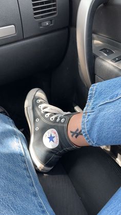 a person wearing converse shoes sitting in the driver's seat