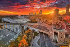 the sun is setting over niagara falls and it's bridge that spans across the river