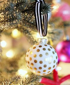 a white and gold ornament hanging from a christmas tree with polka dots on it