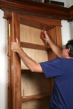 a man working on a wooden cabinet in a room