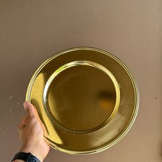 a person holding a gold plate in their left hand and pointing to it on the wall