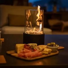 a table topped with a plate of food and a glass vase filled with flames on top of it