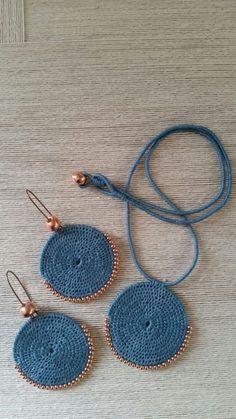 three crocheted circular earrings with copper beads on a blue cord, sitting next to each other