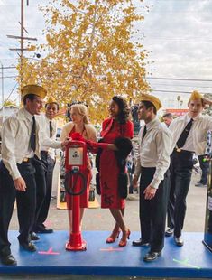 a group of people standing around a red fire hydrant