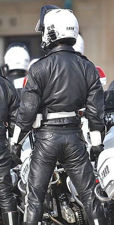 two men in black leather jackets and white helmets are standing next to each other on their motorcycles