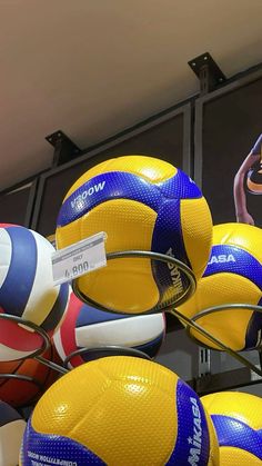 several volleyballs are stacked on top of each other in a display case at a sports store