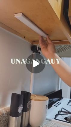 a person is fixing the under cabinet light fixture in their kitchen, with text reading unaganuay above it