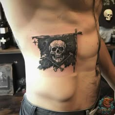 a man's chest with a skull and cross tattoo on the side by person