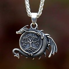 a necklace with a dragon on the front and tree of life on the back, hanging from a silver chain